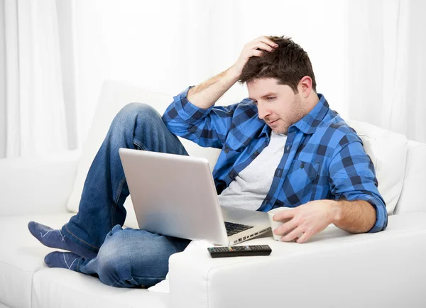 Relaxado homem usando computador em casa sentado no sofá — Fotografia de Stock