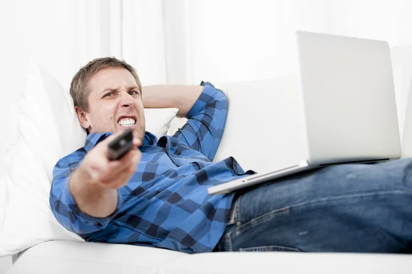 Hombre relajado usando la computadora en casa encendiendo la televisión — Foto de Stock