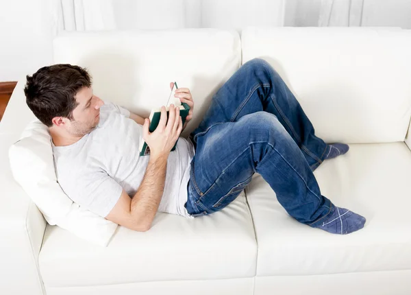 Atractivo hombre leyendo libro o estudiando en el sofá — Foto de Stock