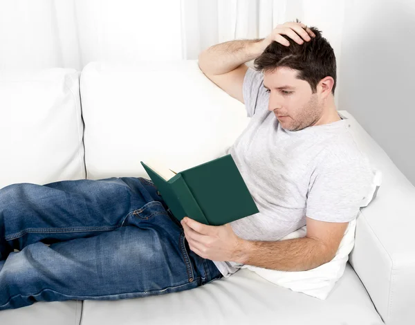 Homem atraente ler livro ou estudar no sofá — Fotografia de Stock