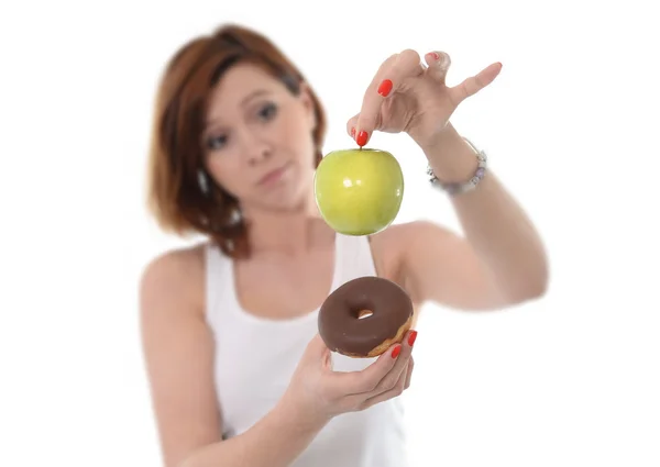 Joven atractivo deporte de pelo rojo Mujer con manzana y pastel en las manos en la opción de postre comida sana versus chatarra aislado en fondo blanco — Foto de Stock