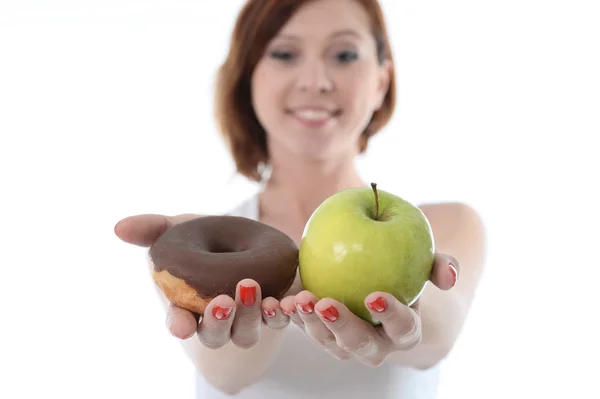 Ung sport kvinna med äpple och choklad donut i händerna i friska kontra skräpmat dessert val isolerad på vit bakgrund — Stockfoto