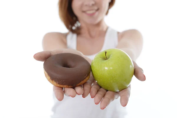 Jonge sport vrouw met apple en chocolade donut in handen in gezonde versus junkfood dessert keuze geïsoleerd op witte achtergrond — Stockfoto