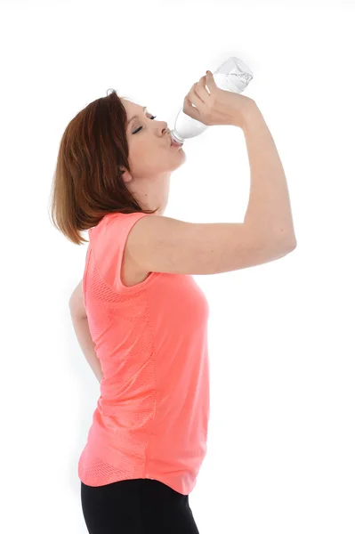 Junge attraktive Sportlerin mit roten Haaren trinkt Wasser in der Flasche — Stockfoto