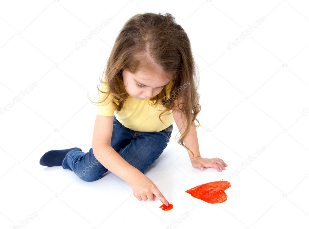 Artistic sweet little girl painting with finger a red heart