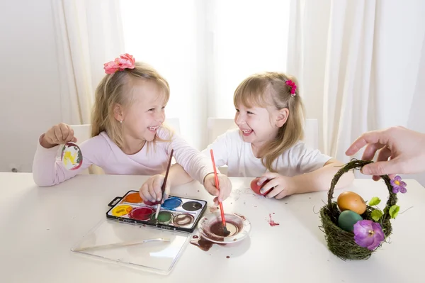 Happy blonded girls painting a easter eggs white window — Stock Photo, Image