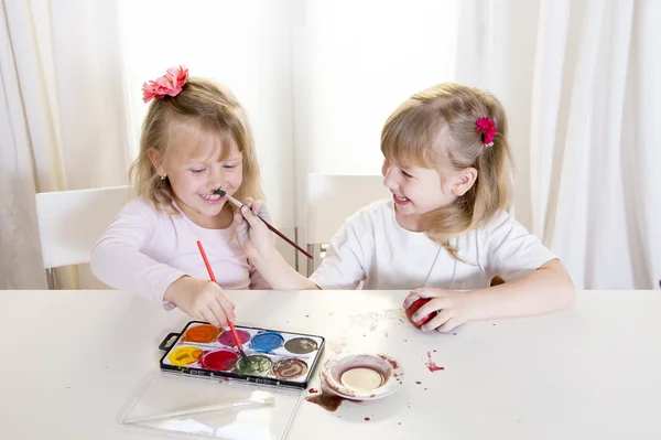 Happy blonded girls painting a easter eggs white window — Stock Photo, Image