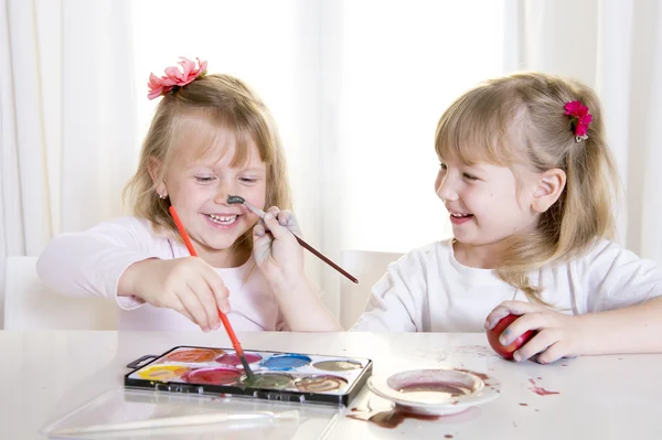 Meninas loiras felizes pintando uma páscoa ovos janela branca — Fotografia de Stock