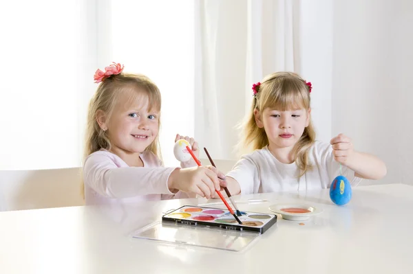 Happy blonded girls painting a easter eggs white window — Stock Photo, Image