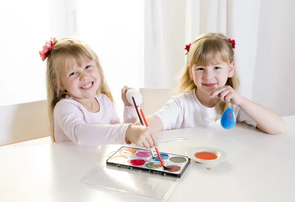 Niñas rubias felices pintando una ventana blanca huevos de Pascua —  Fotos de Stock