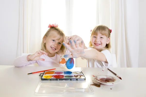 Niñas rubias felices pintando una ventana blanca huevos de Pascua —  Fotos de Stock