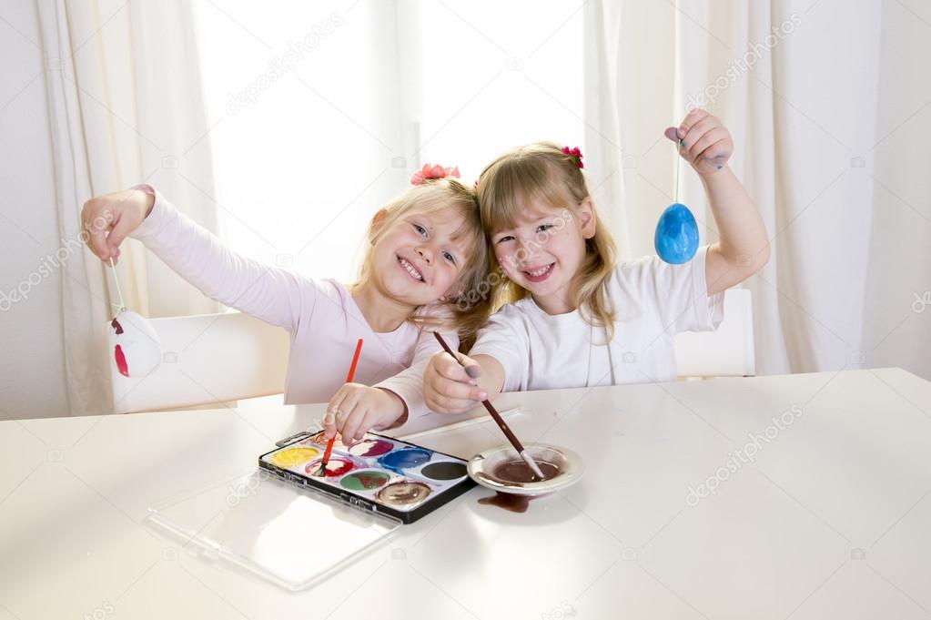 happy blonded girls painting a easter eggs white window 