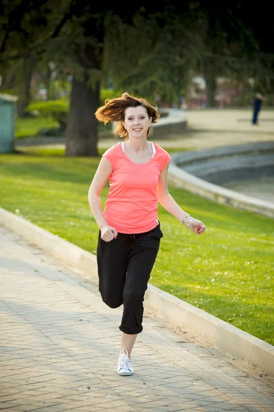 Hübsche rothaarige Frau läuft im Park — Stockfoto