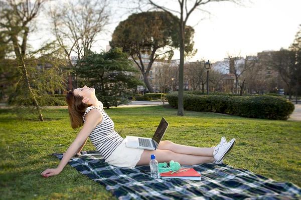 Bonita mujer pelirroja trabajando en un ordenador portátil en un parque — Foto de Stock