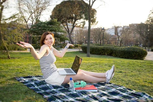 Pretty red haired woman working on laptop in a park — Stock Photo, Image