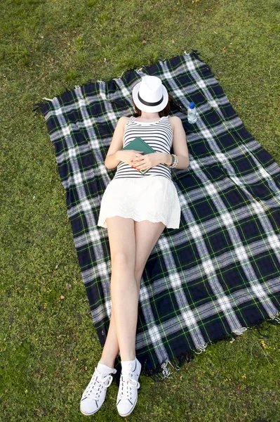 Onun yüzüne bir parkta bir şapka ile uyuyan kadın — Stok fotoğraf