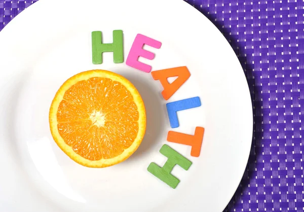 Gehalveerde vers en gezond oranje vruchten stillife en gezondheid woord op plaat — Stockfoto