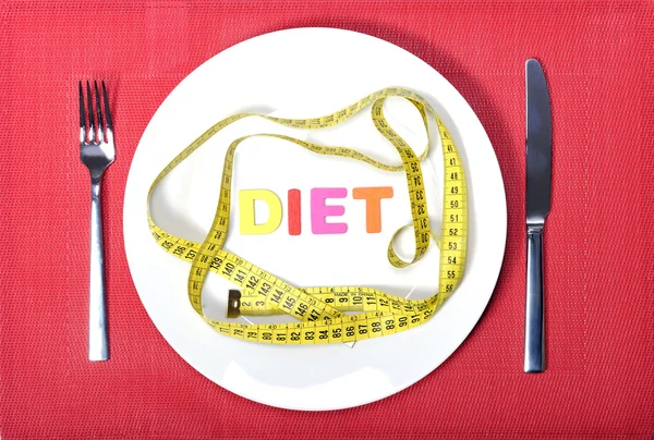 Medir la cinta como comida en el plato con tenedor y cuchillo en el concepto de dieta —  Fotos de Stock