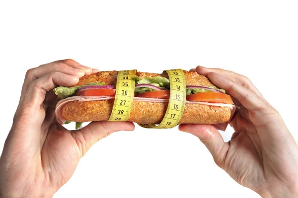 Kéz tartja intézkedés szalagot a diéta fogalmát csomagolva növényi szendvics — Stock Fotó