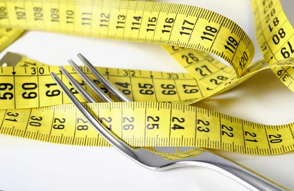 Garfo de prata envolto em fita métrica na dieta e conceito de excesso de peso — Fotografia de Stock