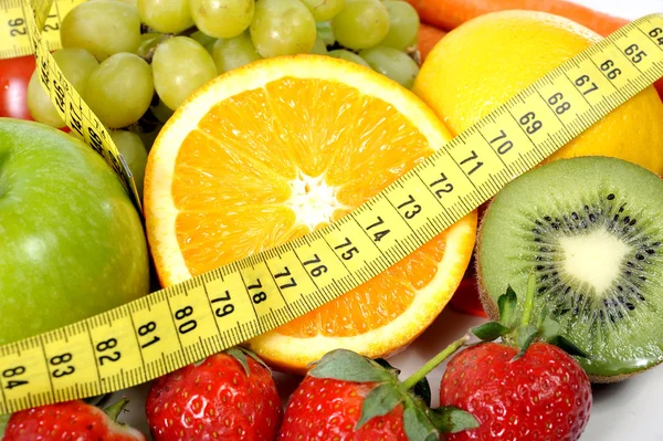 Mistura de frutas frescas e legumes embrulhados em fita métrica amarela — Fotografia de Stock