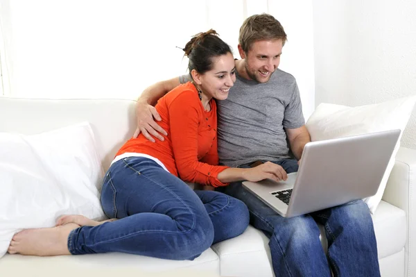 Casal feliz trabalhando em seu laptop no sofá — Fotografia de Stock