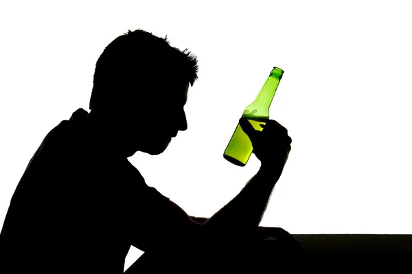 Silhouette eines alkoholisierten, Bierflaschen trinkenden Mannes, der depressiv ist und in ein Suchtproblem verfällt — Stockfoto