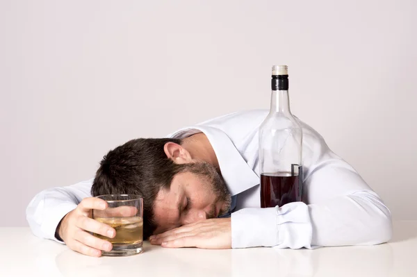 Empresário vestindo camisa azul bêbado na mesa em fundo claro — Fotografia de Stock