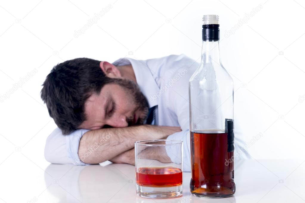 Businessman wearing blue shirt drunk at desk on white background