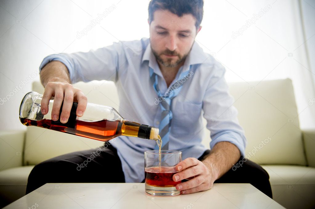 Businessman wearing blue shirt drunk at desk on white background