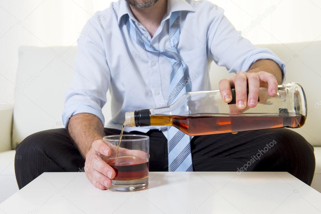 Businessman wearing blue shirt drunk at desk on white background