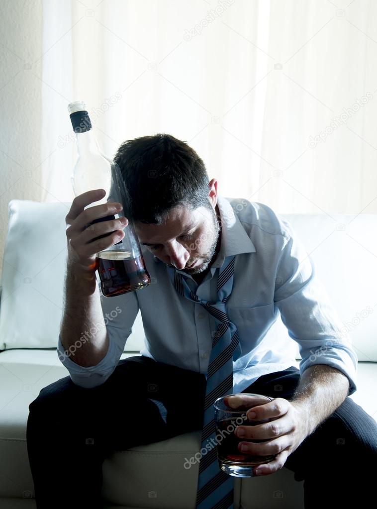 Businessman wearing blue shirt drunk at desk on white background