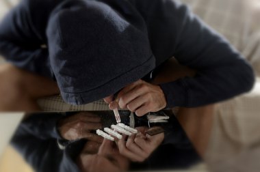 Genç uyuşturucu bağımlısı hood koklama ve haddelenmiş banknot ayna üzerinde kokain çizgilerle burundan enfiye şeklinde çekmek yalnız adam