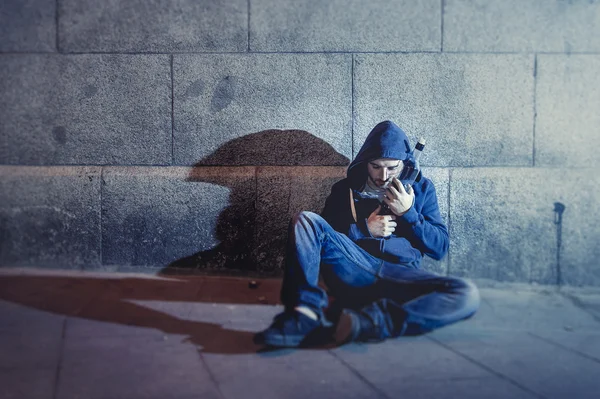 Hombre grunge alcohólico sentado en la esquina de la calle bebiendo botella de alcohol — Foto de Stock