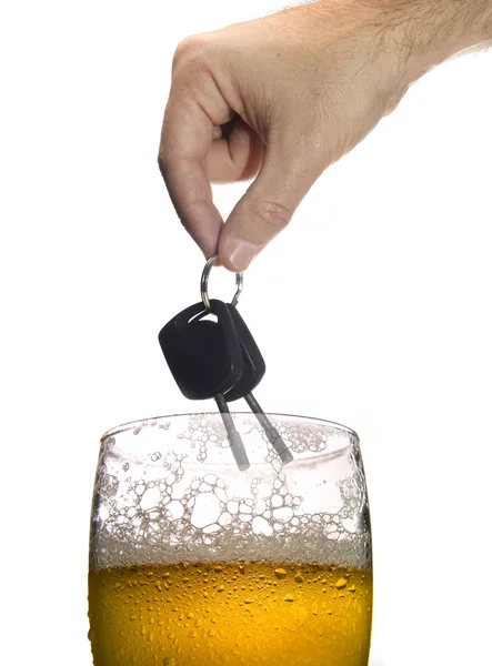 Άνθρωπος χέρι που κρατά τα κλειδιά του αυτοκινήτου πάνω από το ποτήρι της μπύρας που απομονώνονται σε λευκό — Φωτογραφία Αρχείου