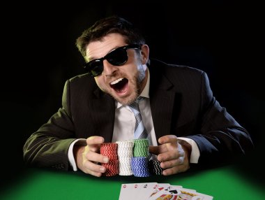 happy young attractive man grabbing poker chips after winning bet gambling clipart