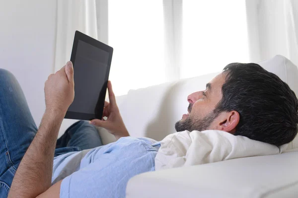 Молодий щасливий привабливий чоловік за допомогою цифрової колодки або планшета сидить на дивані — стокове фото