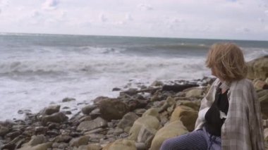 Yaşlı yaşlı bir kadın okyanus kıyısında otururken ya da rüzgarlı bir günde acıdan kıvranırken dinleniyor. Kırık kol eli. Alçıtaşı bandajlı yaşlı kadın bileği yazın dışarıda acı çekiyor.