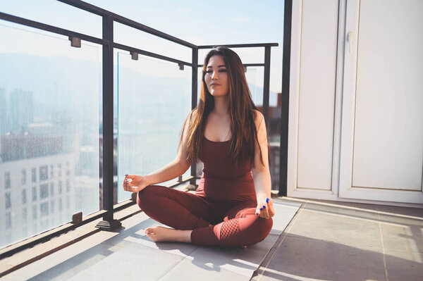 Beautiful Asian smiling fit woman doing yoga on sunny balcony in sport suit. Young happy lady on terrace at summertime. Big city view. Sports exercises and gymnastics, healthy way of life concept. Royalty Free Stock Images