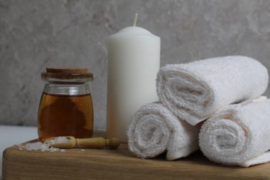 Vücut masajı için yağ beyaz mum havluları salyangoz salyangoz tahta tepside gri arka plan görünümlü. Spa rahatlama masajı. Vücut bakımı.