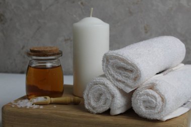 Vücut masajı için yağ beyaz mum havluları salyangoz salyangoz tahta tepside gri arka plan görünümlü. Spa rahatlama masajı. Vücut bakımı.