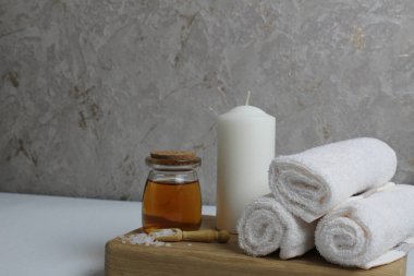 Vücut masajı için yağ beyaz mum havluları salyangoz salyangoz tahta tepside gri arka plan görünümlü. Spa rahatlama masajı. Vücut bakımı.