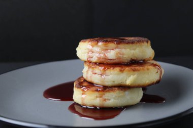 Kahvaltılık peynirli kekler krep. Üç parça slayt üst üste ve siyah arka planda vişne sosu kırmızısı..