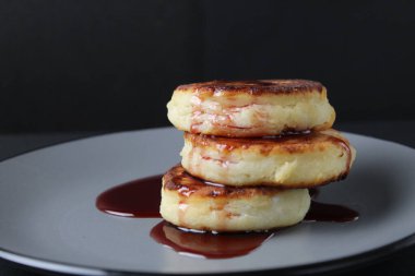 Kahvaltılık peynirli kekler krep. Üç parça slayt üst üste ve siyah arka planda vişne sosu kırmızısı..