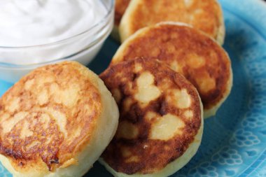Cheesecakes krepleri ekşi kremanın yanındaki mavi tabağın üzerinde. Kahvaltı süzme peynirli ev yapımı kahvaltı..
