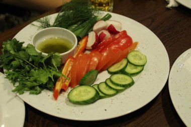 Sebze dilimleri salatalık domatesler turplar dereotlu maydanoz ve kafeterya restoranında sarı yeşil sos. Tabakta sebzeler.