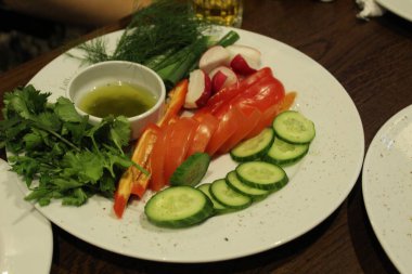 Sebze dilimleri salatalık domatesler turplar dereotlu maydanoz ve kafeterya restoranında sarı yeşil sos. Tabakta sebzeler.