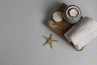 Flatlay spa masaj tedavileri üst görünüm düzeni. Deniz yıldızı beyazından kıvrılmış havlular banyo tuzu yağlı mumlar. Kişisel bakım..