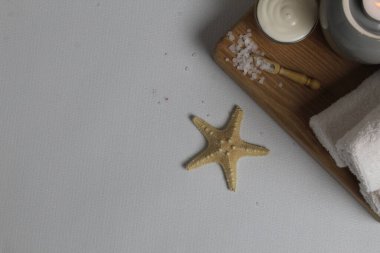 Flatlay spa masaj tedavileri üst görünüm düzeni. Deniz yıldızı beyazından kıvrılmış havlular banyo tuzu yağlı mumlar. Kişisel bakım..