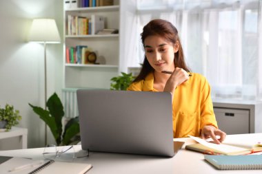 Gülümseyen ve pozitif hisseden. Evde bilgisayarla çalışan mutlu Asyalı kadın serbest yazar. Çevrimiçi öğrenim gören çekici iş kadını, dizüstü bilgisayar, web sörfü bilgileri veya internet mağazasından alışveriş yapıyor.